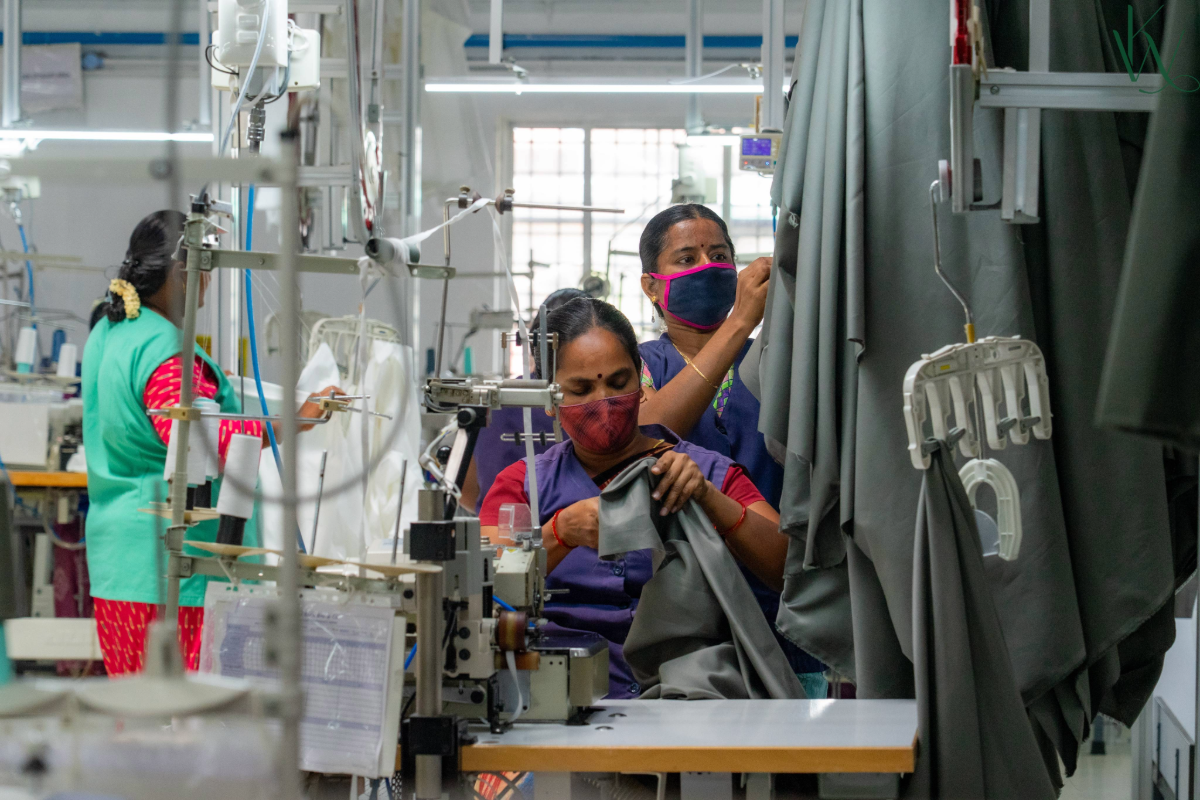 Workers in a factory setting with machinery and materials.